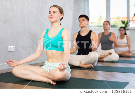 Group of young people meditating in a lotus pose. 135886191