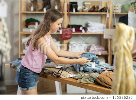 Teenage girl chooses denim shorts in store Teenage girl chooses denim shorts in store 135886283