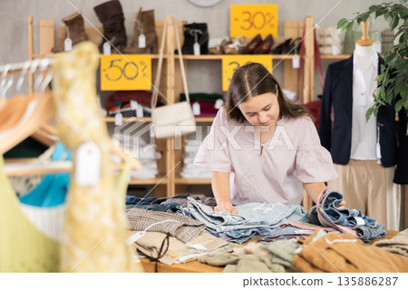 Teenager chooses jeans on sale 135886287