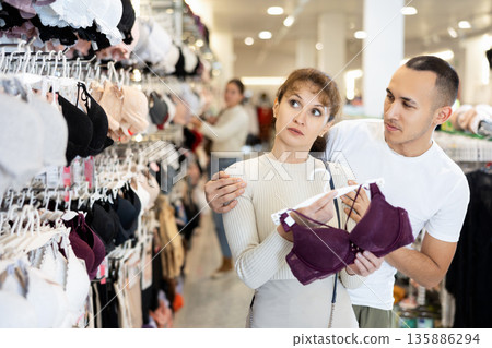 Young couple choosing nice brassiere in clothing store Young couple choosing nice brassiere in clothing store 135886294