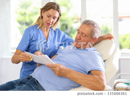 Woman doctor give senior patient medical documents for review before carrying out cosmetic procedure Woman doctor give senior patient medical documents for review before carrying out cosmetic procedure 135886361