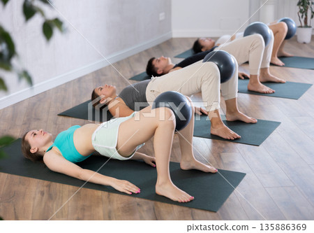 Young people doing softball pilates in studio. Young people doing softball pilates in studio. 135886369