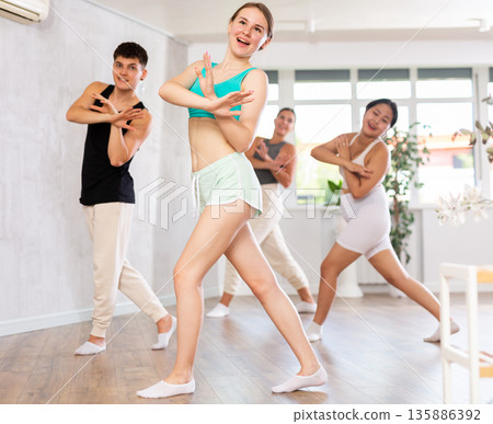 Group of young people dancing indoors. 135886392
