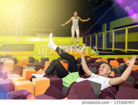 Joyful guy jumping into foam pit at indoor trampoline arena Joyful guy jumping into foam pit at indoor trampoline arena 135886407