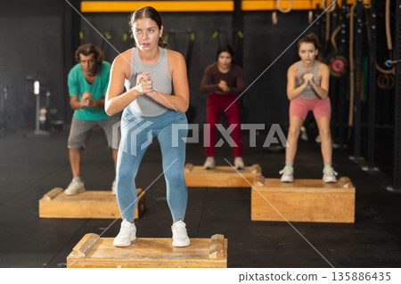 Young woman stepping on box at Crossfit workout Young woman stepping on box at Crossfit workout 135886435