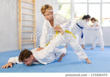 Parent with child athletes in pair conduct training battle in oriental fighting technique Parent with child athletes in pair conduct training battle in oriental fighting technique 135886470
