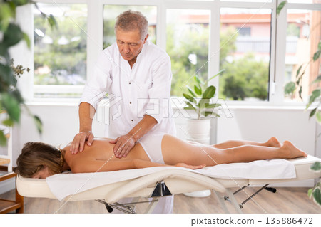 male masseur giving massage to female patient male masseur giving massage to female patient 135886472