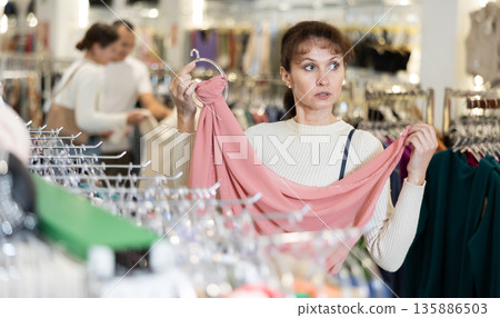 Adult woman choosing scarf in store 135886503