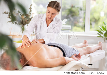 masseuse giving massage to male patient 135886567