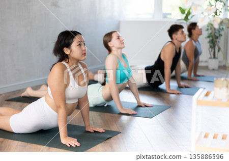 Young teen Asian girl performs pose dog muzzle up - cobra, Urdhva Mukha Shvanasana- Bhujangasana Young teen Asian girl performs pose dog muzzle up - cobra, Urdhva Mukha Shvanasana- Bhujangasana 135886596