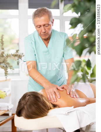 male masseur giving massage to female patient male masseur giving massage to female patient 135886623