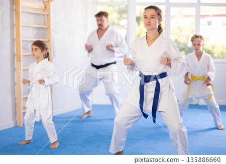 Woman practicing kata routine during family training at karate class 135886660