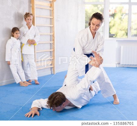 Concentrated woman practicing armlock in sparring with husband at karate training 135886701
