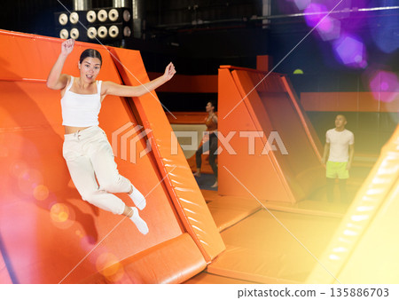Portrait of sporty girl jumping on trampolines in her free time in gaming club Portrait of sporty girl jumping on trampolines in her free time in gaming club 135886703