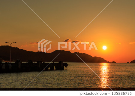 A tranquil sunset scene with the Seto Inland Sea sparkling in the setting sun and the breakwater of Yawatahama Port A tranquil sunset scene with the Seto Inland Sea sparkling in the setting sun and the breakwater of Yawatahama Port 135886755