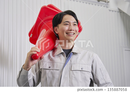 Worker holding a traffic cone, warehouse portrait Worker holding a traffic cone, warehouse portrait 135887058