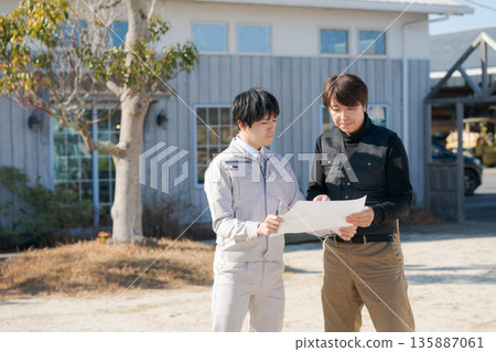 工匠們在房子前查看藍圖 工匠們在房子前查看藍圖 135887061