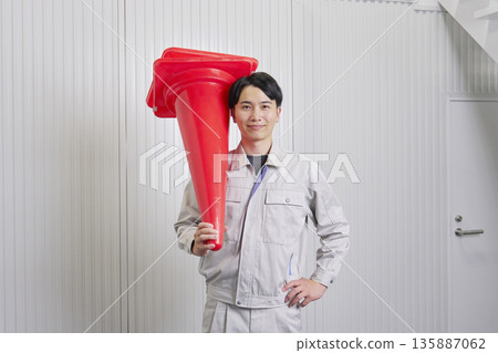Worker holding a traffic cone, warehouse, portrait, looking at camera Worker holding a traffic cone, warehouse, portrait, looking at camera 135887062
