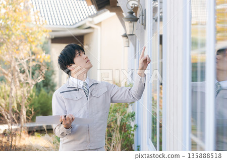 A man in work clothes checking the window from outside A man in work clothes checking the window from outside 135888518