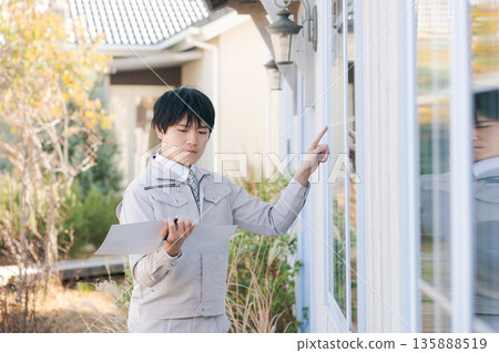 A man in work clothes checking the window from outside A man in work clothes checking the window from outside 135888519