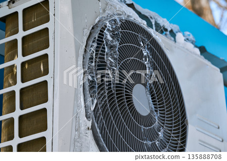 Close-up of frozen industrial equipment and air conditioner covered in thick ice and icicles 135888708