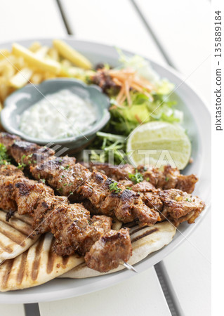 BBQ chicken skewer gyros plate on white table in mykonos restaurant greece BBQ chicken skewer gyros plate on white table in mykonos restaurant greece 135889184