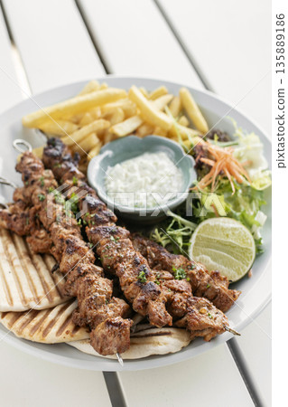 BBQ chicken skewer gyros plate on white table in mykonos restaurant greece BBQ chicken skewer gyros plate on white table in mykonos restaurant greece 135889186