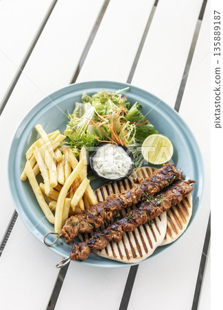 BBQ chicken skewer gyros plate on white table in mykonos restaurant greece BBQ chicken skewer gyros plate on white table in mykonos restaurant greece 135889187