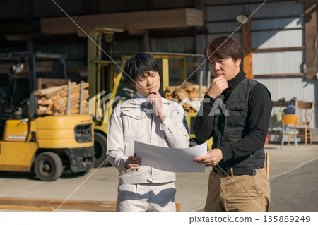 Men looking at blueprints and worrying 135889249