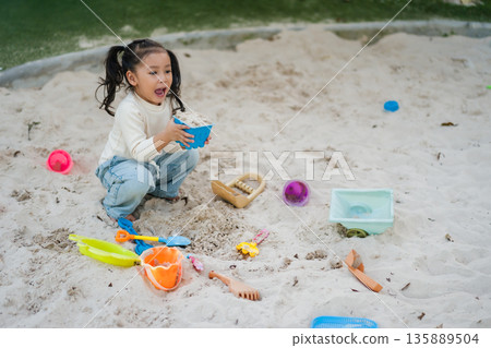 happy child girl playing sand with toy on playground happy child girl playing sand with toy on playground 135889504