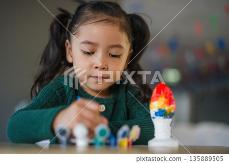 child girl painting plaster statue on table 135889505