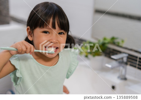 girl child brushing teeth in bathroom 135889508