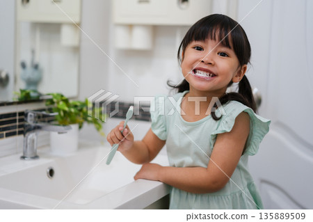girl child brushing teeth in bathroom girl child brushing teeth in bathroom 135889509