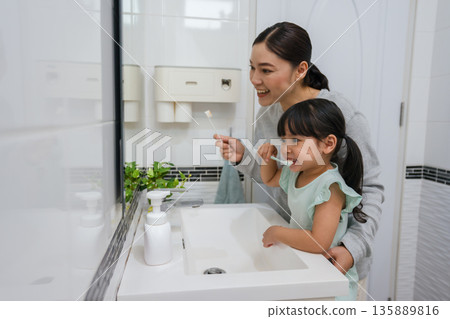 mother teaching girl child to brushing teeth in bathroom 135889816