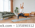 Happy young Asian woman practicing yoga and shoulder stretching  in living room at home 135890312