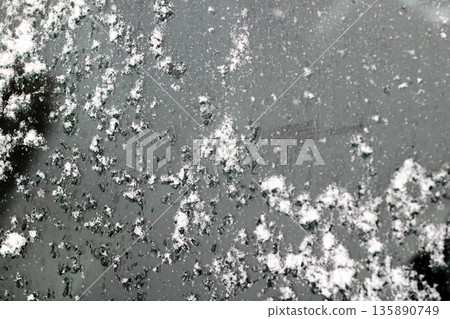 Detailed black and white photograph capturing icy salt residue on city street surface 135890749