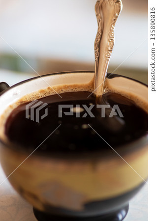 Coffee moment captured, Closeup of dark espresso with swirling crema in rustic kitchen scene 135890816