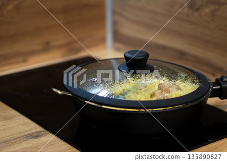 Steam rises from sizzling cookware, Intimate closeup capturing warm kitchen cooking ambiance Steam rises from sizzling cookware, Intimate closeup capturing warm kitchen cooking ambiance 135890827
