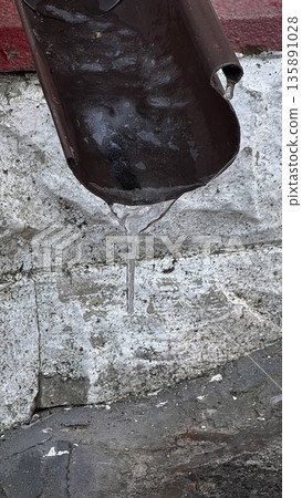 Close-up of water dripping from a brown gutter. Close-up of water dripping from a brown gutter. 135891028