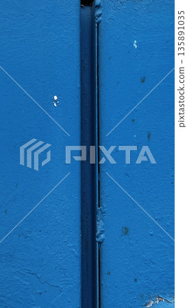 Close-up of a blue wall showcasing unique textures and seams. 135891035