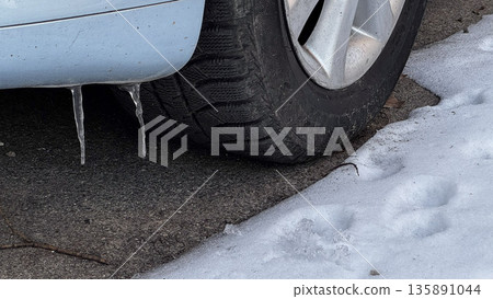 Close-up of a car tire with icicles and snow. 135891044