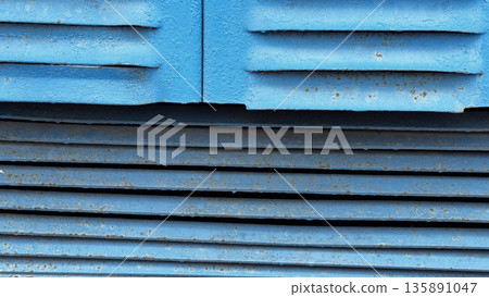 Close-up of weathered blue metal panels showcasing texture. Close-up of weathered blue metal panels showcasing texture. 135891047