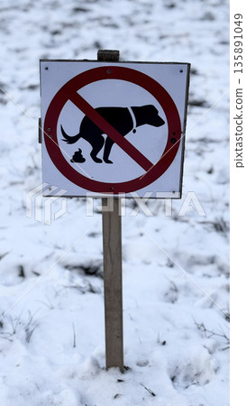 Clear warning sign against dog waste in snowy park. Clear warning sign against dog waste in snowy park. 135891049