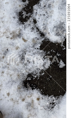 Close-up of snow-covered ground with dark patches. Close-up of snow-covered ground with dark patches. 135891064
