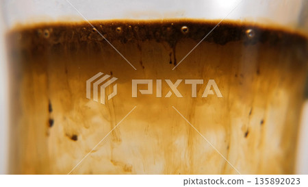 Instant coffee granules falling into hot water and dissolving. Macro shot, morning routine concept  135892023