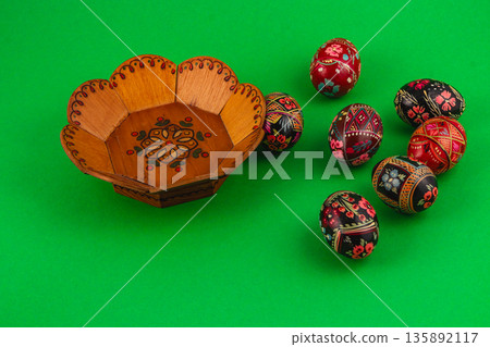 Colorful Easter eggs and a wooden bowl on green background Colorful Easter eggs and a wooden bowl on green background 135892117