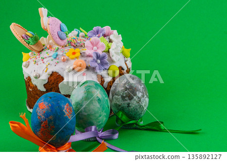 Colorful Easter cake and decorated eggs on green background 135892127