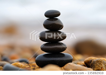 Stacked black stones create a peaceful balance by the ocean shore 135892910