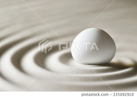 White egg on smooth surface creates gentle ripples in sand 135892928