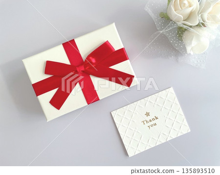 A gift box with a red ribbon and a thank you message card A gift box with a red ribbon and a thank you message card 135893510